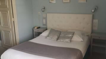 Een slaapkamer met een groot bed, een nachtkastje, een dressoir en een deur.