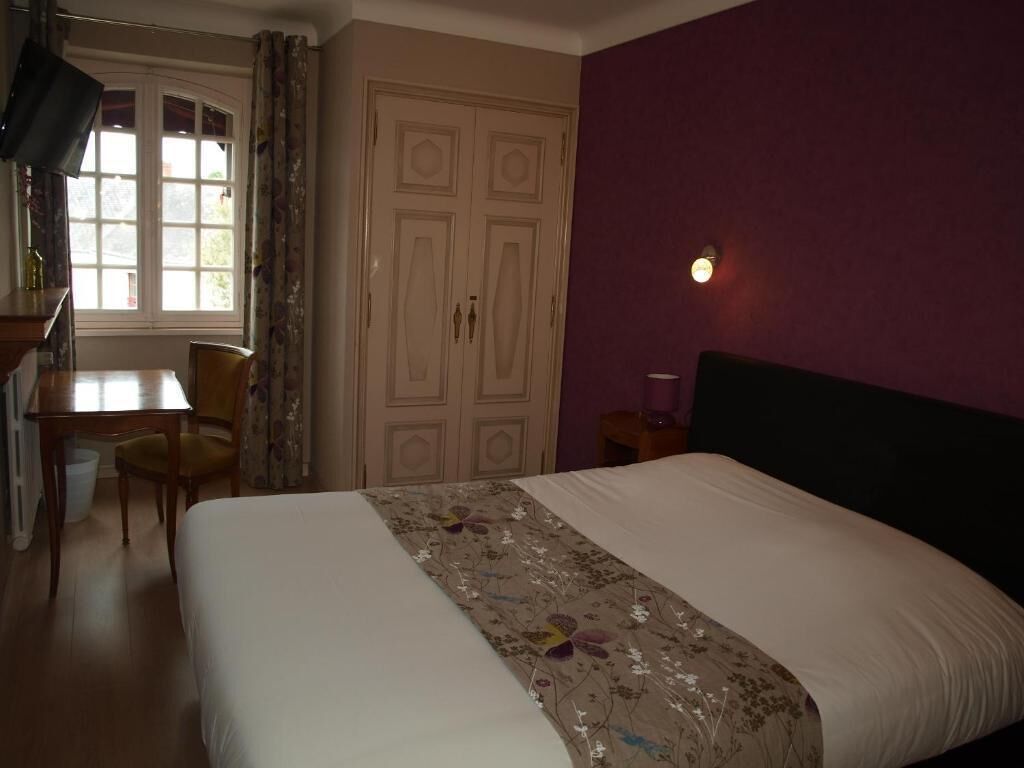 A hotel room with a bed, a desk, and a chair.