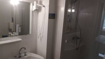 A bathroom with a sink, mirror, and a glass-enclosed shower area.
