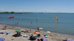 Ein Strand mit badenden, sonnenbäudelnden und Windsurfenden.