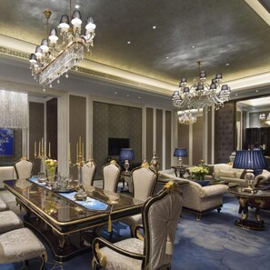 A luxurious dining room with a long table, elegant chairs, and ornate chandeliers.