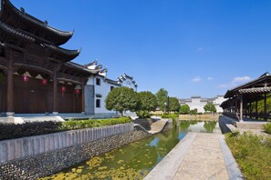 A traditional courtyard with a stone pathway, a small pond, and classical architecture.