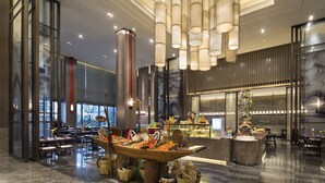 Un'ampia hall con un'esposizione centrale di una barca in legno, un lampadario moderno e un'area bar.