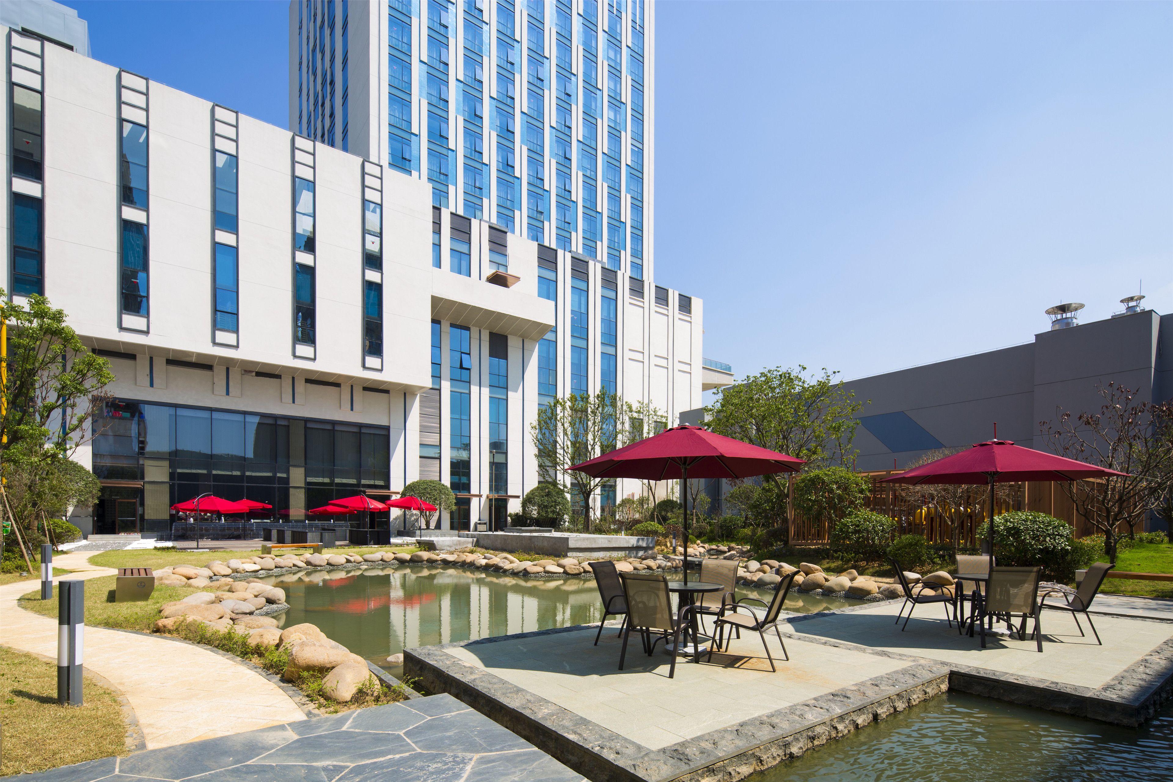 A modern building with a pool area, outdoor seating, and a clear sky.