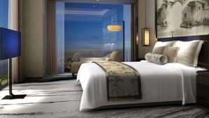 Una camera d'albergo moderna con un letto grande, una TV a schermo piatto e vista sulla città dalla finestra.