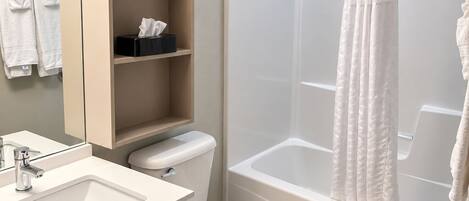 Un baño moderno con lavamanos, inodoro y ducha.