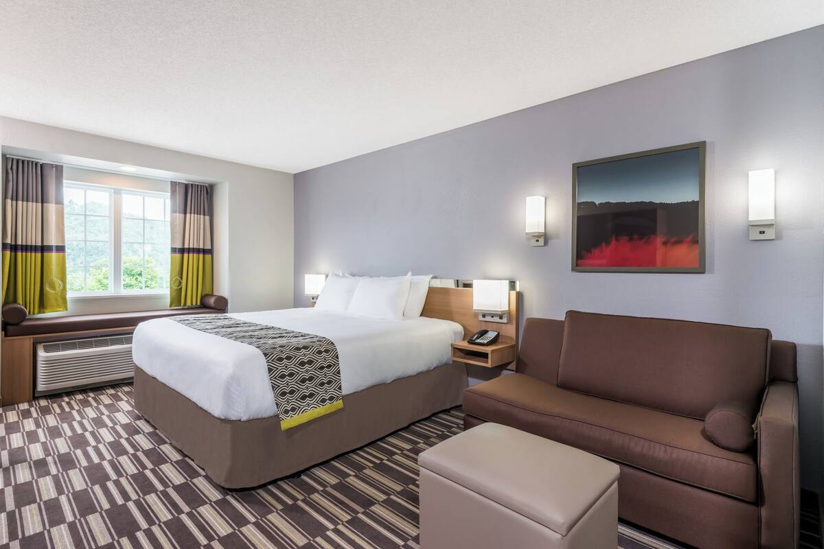 Une chambre d’hôtel avec un grand lit, un canapé, une petite table et un tableau au mur.