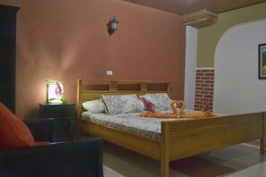 A bedroom with a wooden bed, a nightstand with a lamp, and a chair. - Rustico Santa Teresa (Cóbano)