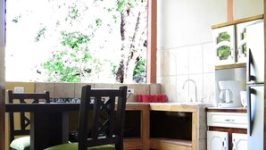 A compact kitchen with a dining table, chairs, a coffee maker, and a refrigerator. - Rustico Santa Teresa (Cóbano)