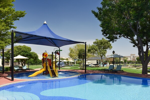 Une piscine avec un toboggan et un espace ombragé.