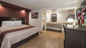 A hotel room with a bed, a desk, a mirror, a sink, and a shower area. - Red Roof Inn Wildwood - Cape May/ Rio Grande (Rio Grande)