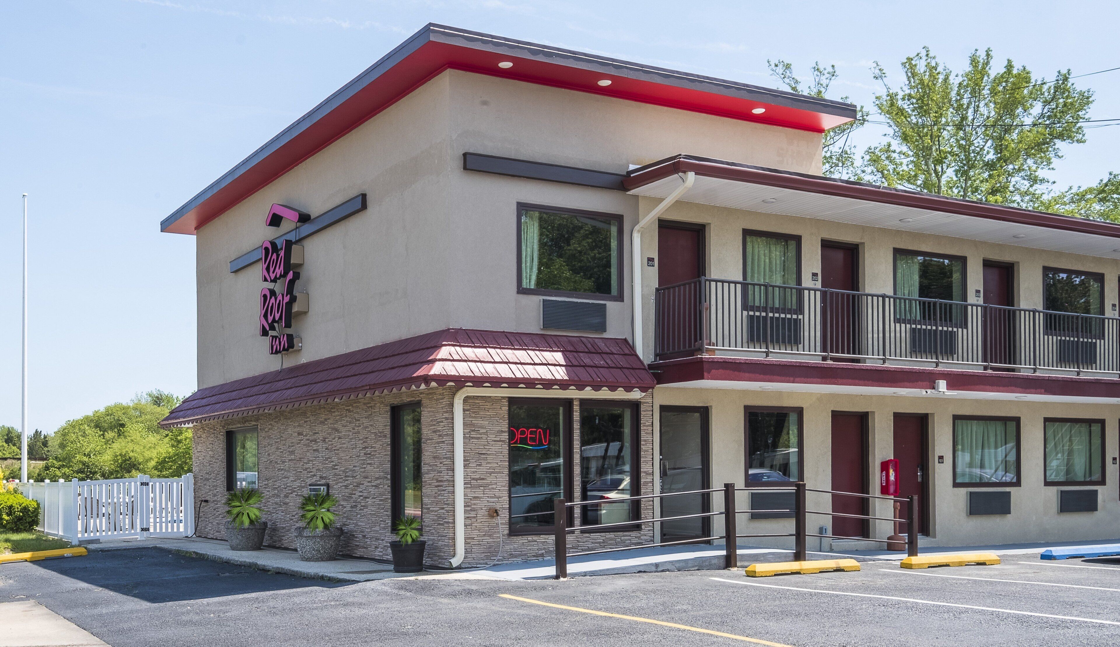 A two-story building with a red awning, a sign reading 'Red Roof Inn,' and a parking lot in front.