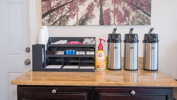 A kitchen counter with a coffee maker, a bottle of coffee creamer, and a set of disposable cups. - Red Roof Inn Wildwood - Cape May/ Rio Grande (Rio Grande)