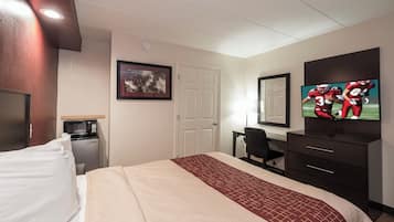 Ein Hotelzimmer mit Bett, Schreibtisch, Fernseher, Mikrowelle und einer Tür.