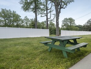 A picnic table in a grassy area with white fences and trees in the background. - Red Roof Inn Wildwood - Cape May/ Rio Grande (Rio Grande)