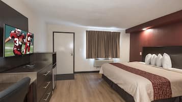 A hotel room with a bed, a desk, a television, and a window with curtains.