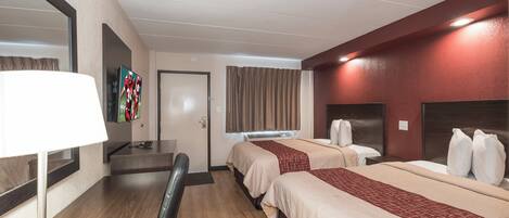 A hotel room with two beds, a desk, a chair, a TV, and a mirror.