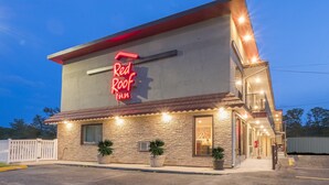 A Red Roof Inn with a stone facade, a red neon sign, and a well-lit entrance. - Red Roof Inn Wildwood - Cape May/ Rio Grande (Rio Grande)