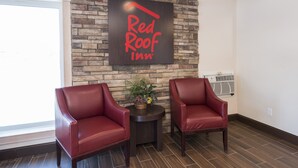 A Red Roof Inn sign on a stone wall, two leather chairs, a small table with a plant, and an air conditioning unit. - Red Roof Inn Wildwood - Cape May/ Rio Grande (Rio Grande)