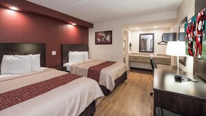 A hotel room with two beds, a desk, a mirror, and a television. - Red Roof Inn Wildwood - Cape May/ Rio Grande (Rio Grande)