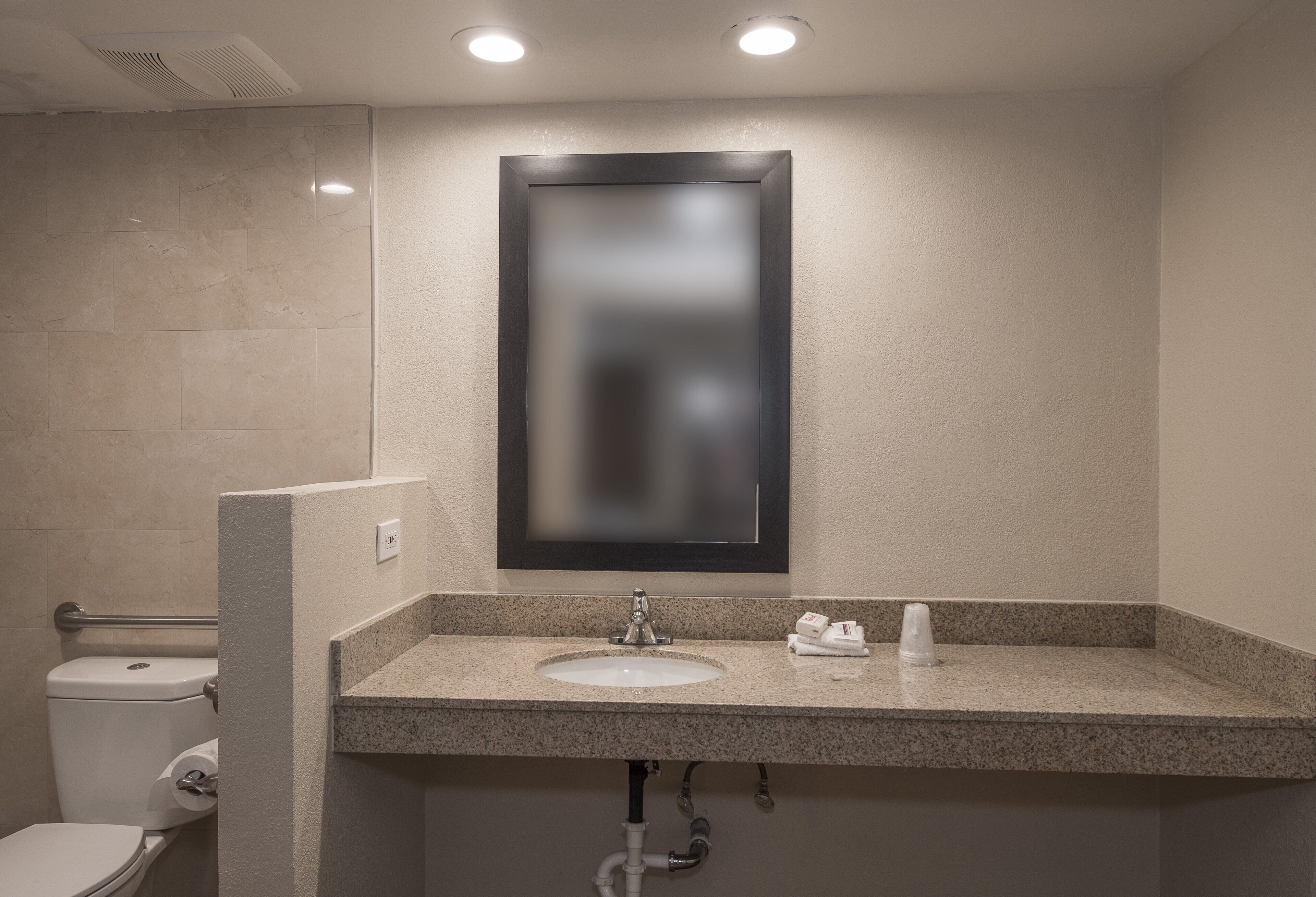 Un baño con inodoro, lavamanos y espejo.