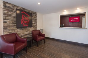 A Red Roof Inn lobby with stone wall decor, two leather chairs, and a sign indicating free Wi-Fi in all rooms. - Red Roof Inn Wildwood - Cape May/ Rio Grande (Rio Grande)