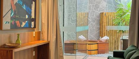 A modern bathroom with a glass shower enclosure, wooden vanity, and a green sofa.