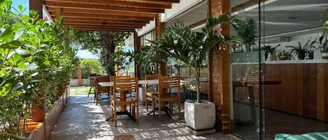 A covered outdoor seating area with wooden furniture and potted plants.