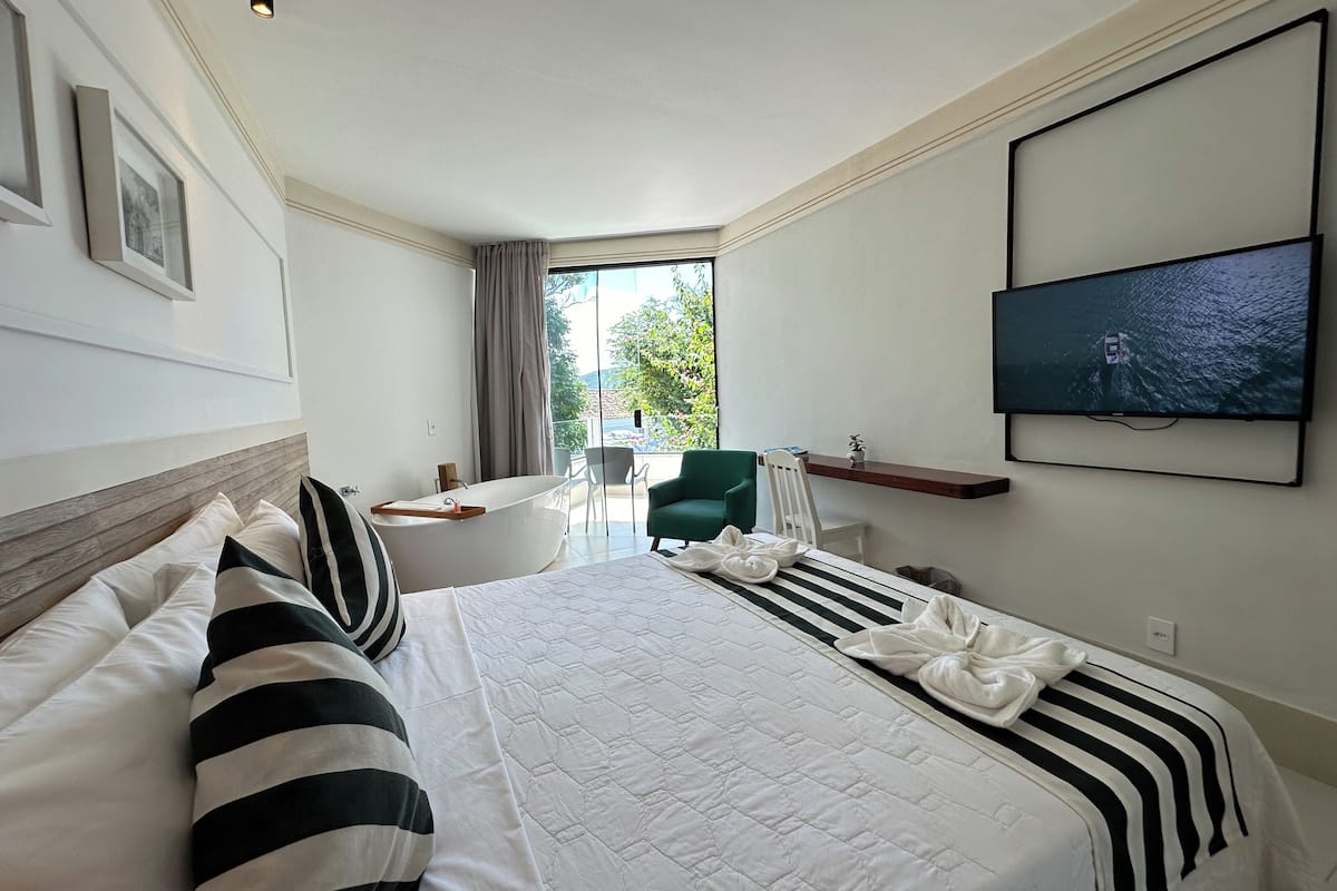 Une chambre d’hôtel avec un grand lit, une télévision, un bureau et une vue sur l’extérieur.