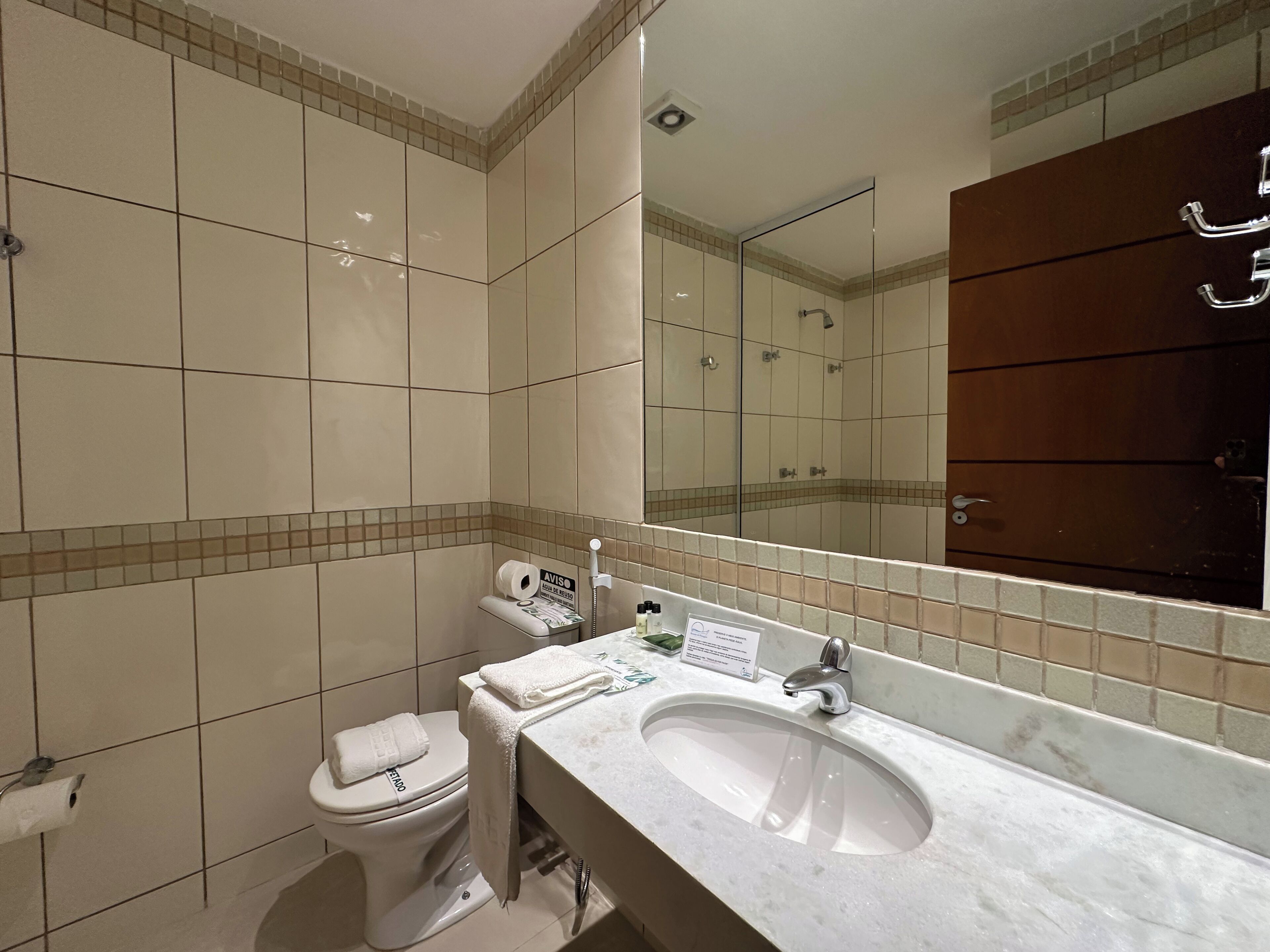 A modern bathroom with a white sink, a toilet, and a large mirror.