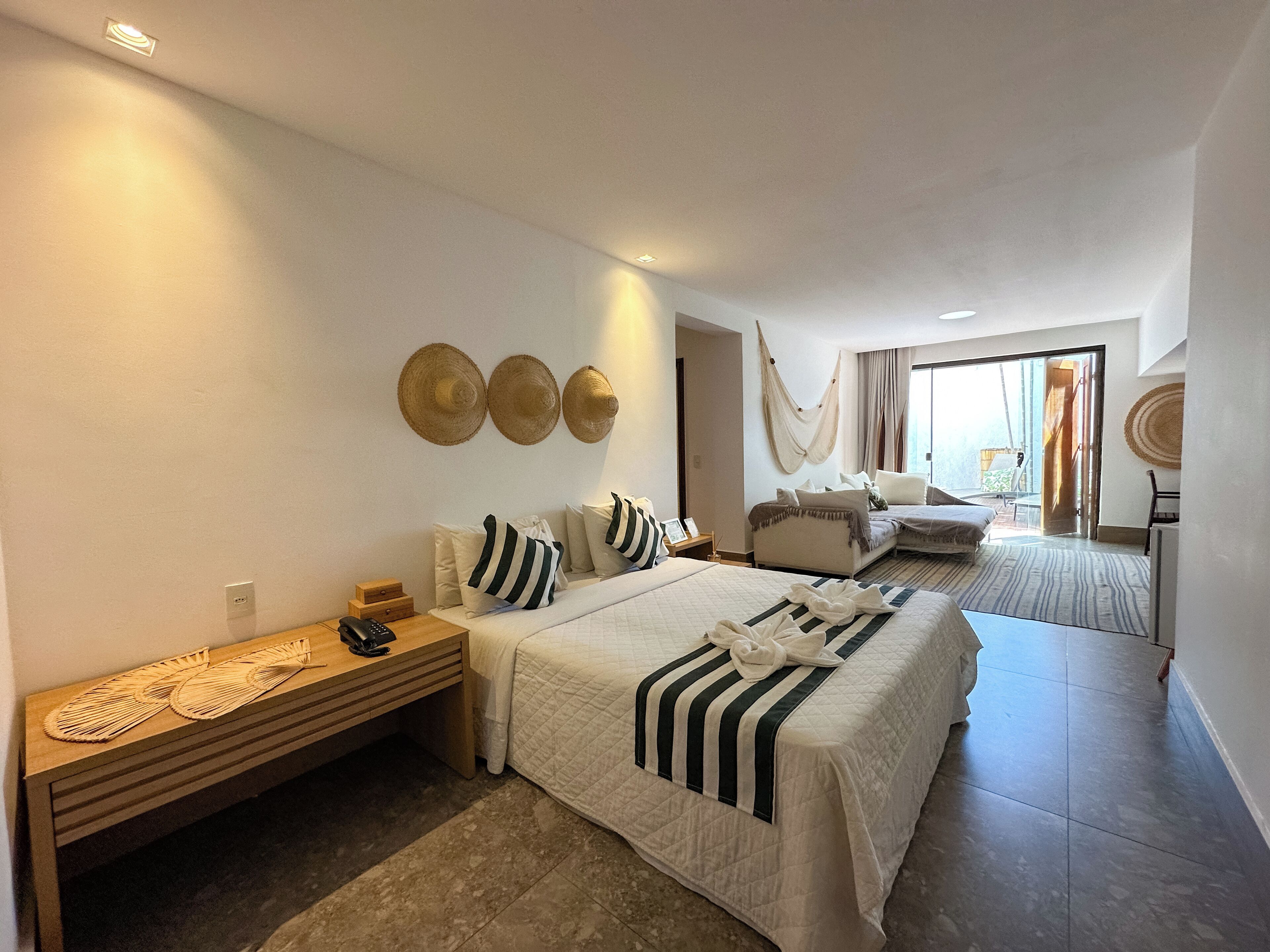A hotel room with two beds, a wooden nightstand, a bedside table, and a large window with a view.