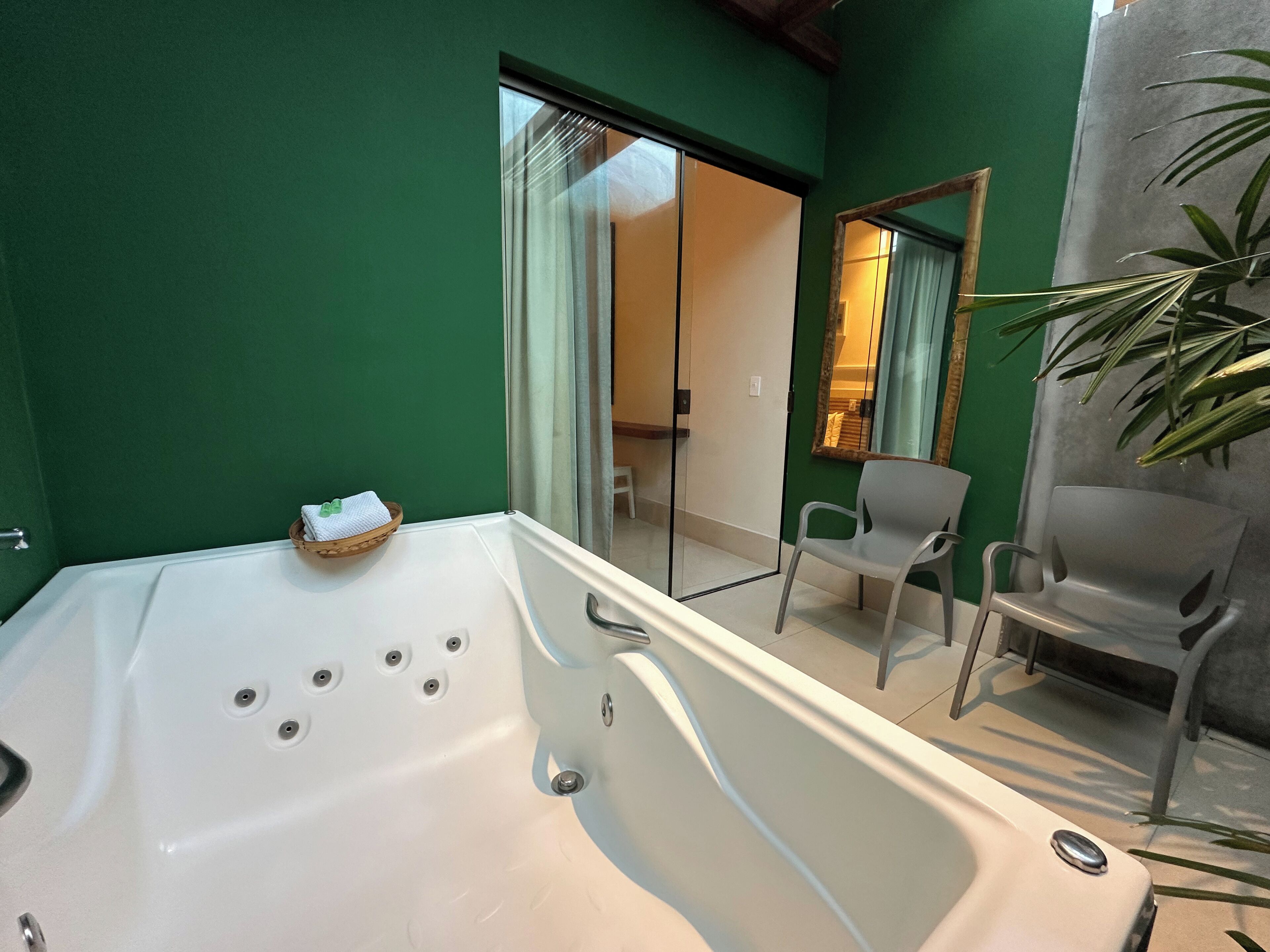 Un baño moderno con una bañera grande, cabina de ducha con mampara de cristal y zona de estar con sillas.