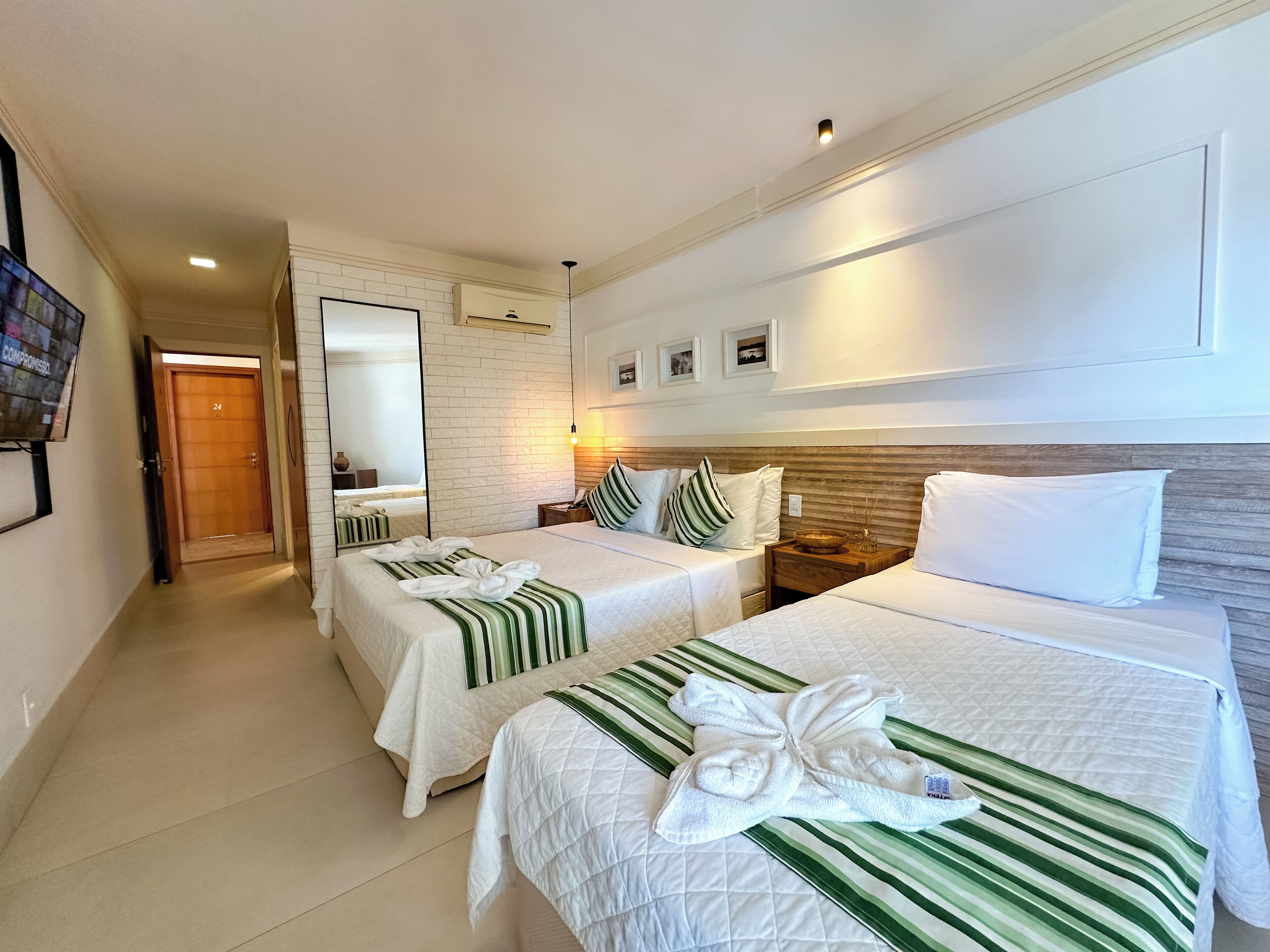A hotel room with two beds, a large mirror, and a wooden headboard.