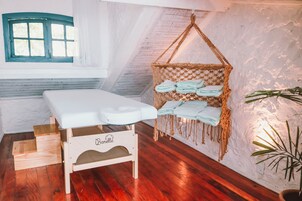 Una habitación acogedora con un banco de madera, una hamaca con toallas y vistas a través de una ventana con marco azul.