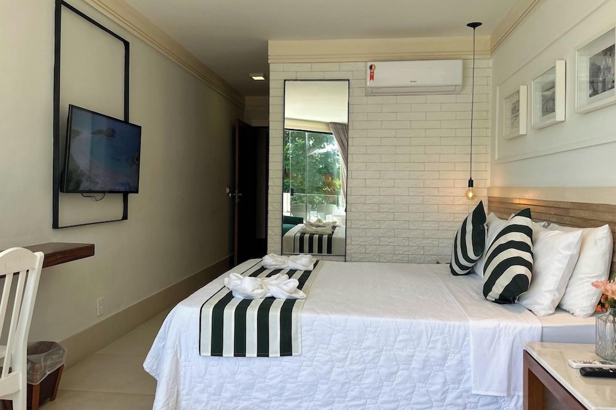 Habitación de hotel con cama, televisión, escritorio y vistas al exterior.