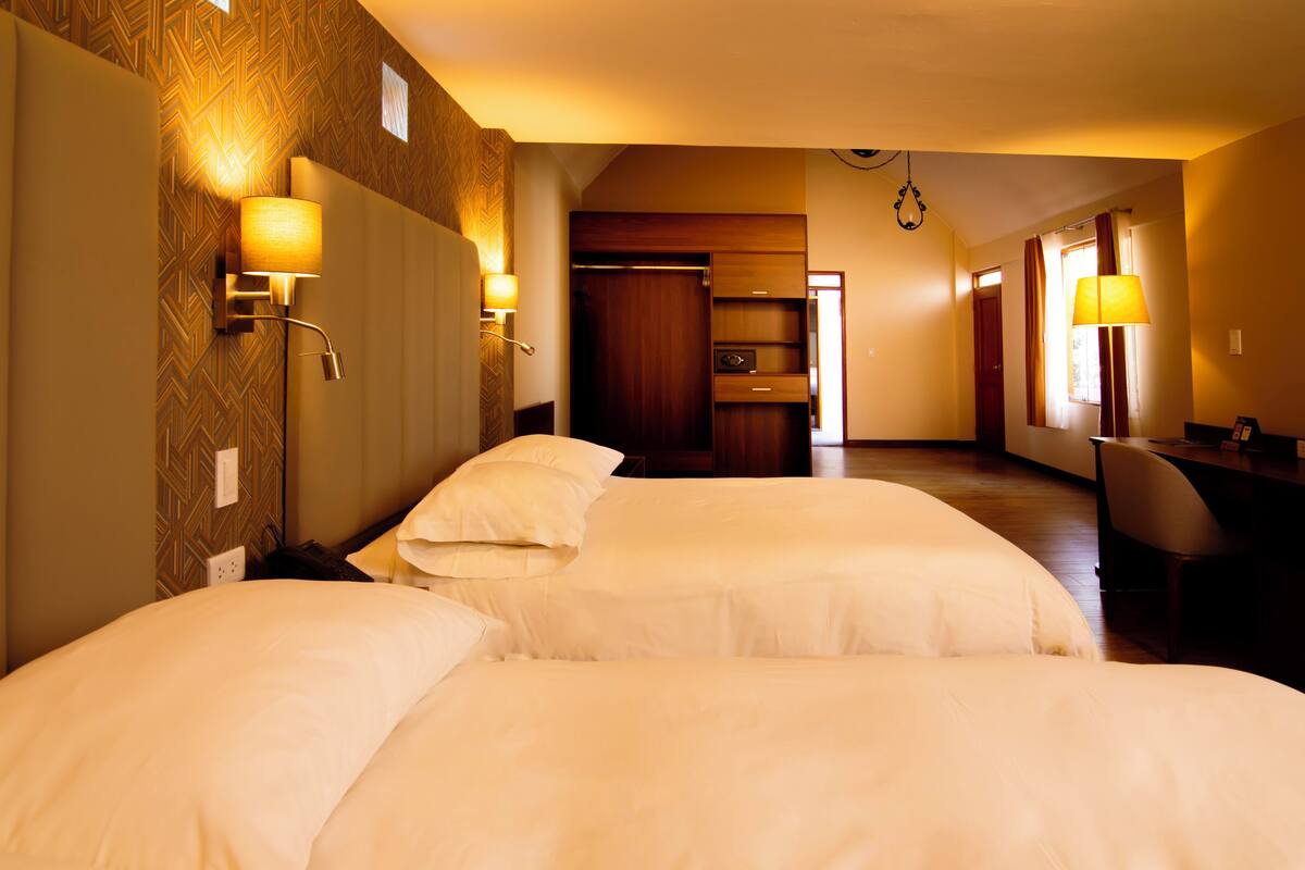 Ett hotellrum med två sängar, ett skrivbord och en garderob.