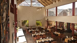 A spacious restaurant with high ceilings, large windows, and a rustic interior. - El Refugio Hotel Colca (Chivay)