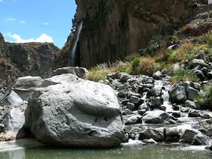 A natural landscape with a waterfall, rocky terrain, and a body of water. - El Refugio Hotel Colca (Chivay)