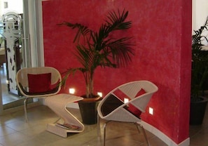 A room with two white chairs, a red wall, and a potted plant. - Hotel Emperador (Jesolo)