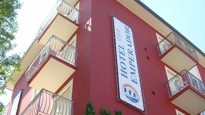 Edifício de hotel com fachada vermelha, várias varandas e uma placa indicando que é um hotel.