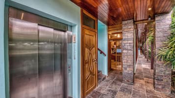 An elevator, a wooden door, a stone pillar, and a hallway with a tiled floor.