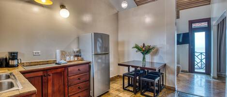 Una cocina con muebles de madera, un refrigerador de acero inoxidable, una cafetera y una mesa de comedor con sillas.