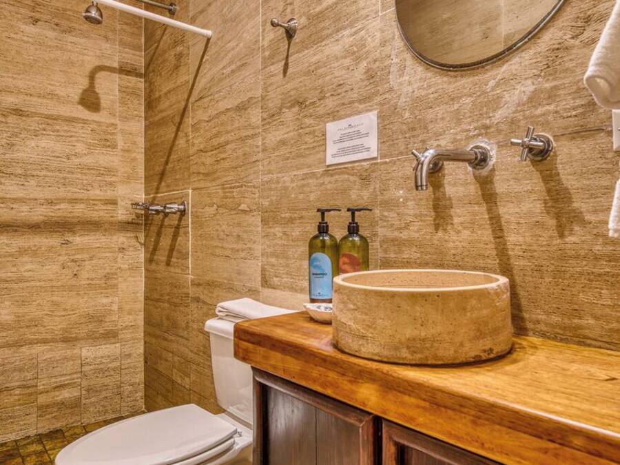 Une salle de bain équipée de toilettes, d’un lavabo, d’un miroir, d’une douche et de meubles en bois.