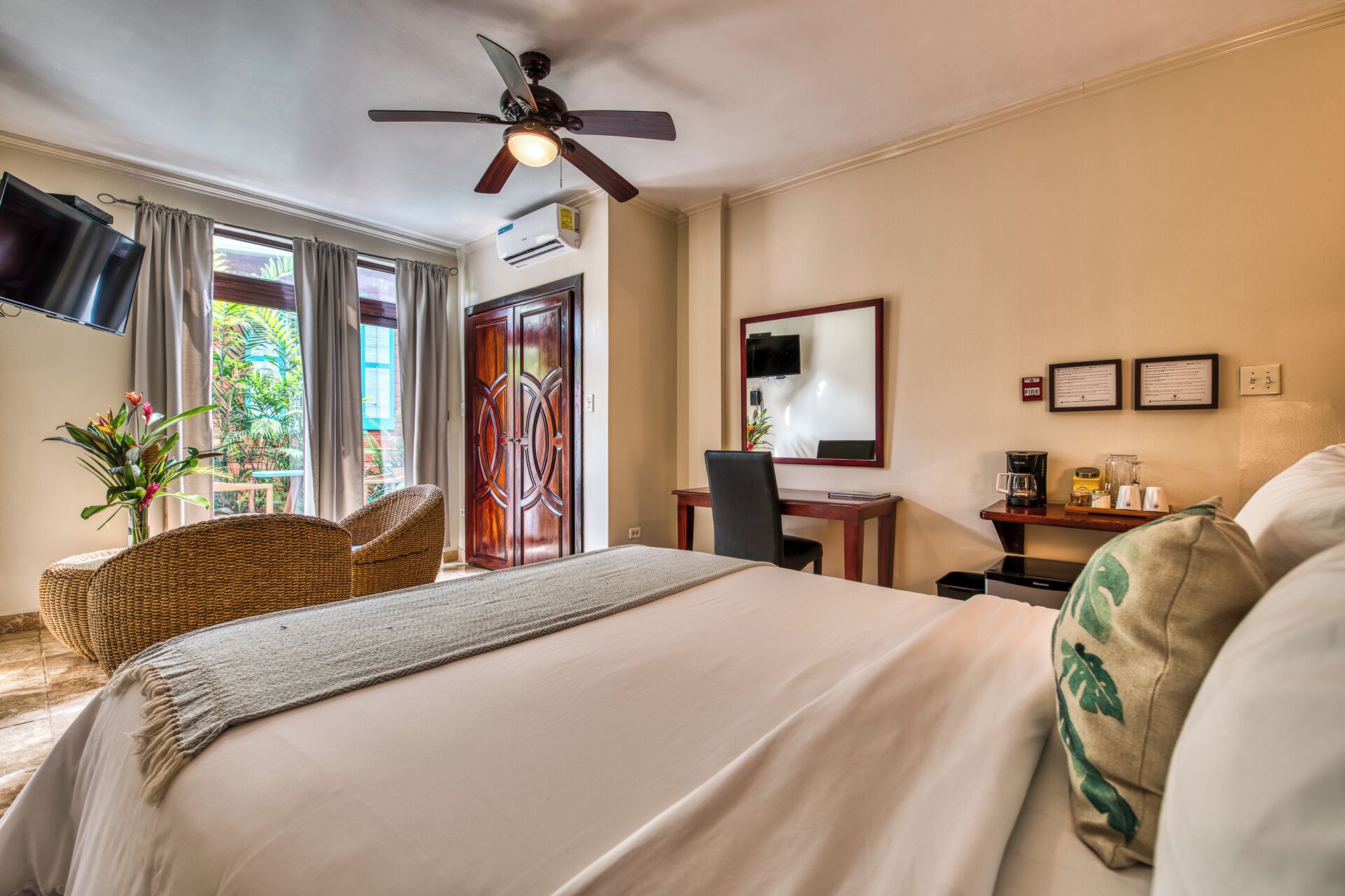 Une chambre d’hôtel équipée d’un lit, d’un bureau, d’une chaise, d’une télévision et d’un ventilateur de plafond.
