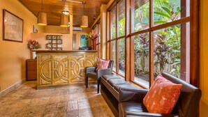 A reception area with a wooden reception desk, a bench, and a large window with a view of greenery.