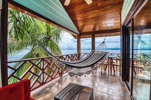 Una hamaca en un balcón con vista al mar y palmeras.