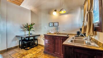 Una cocina con techo de madera, un lavamanos, una encimera y una mesa de comedor con sillas.
