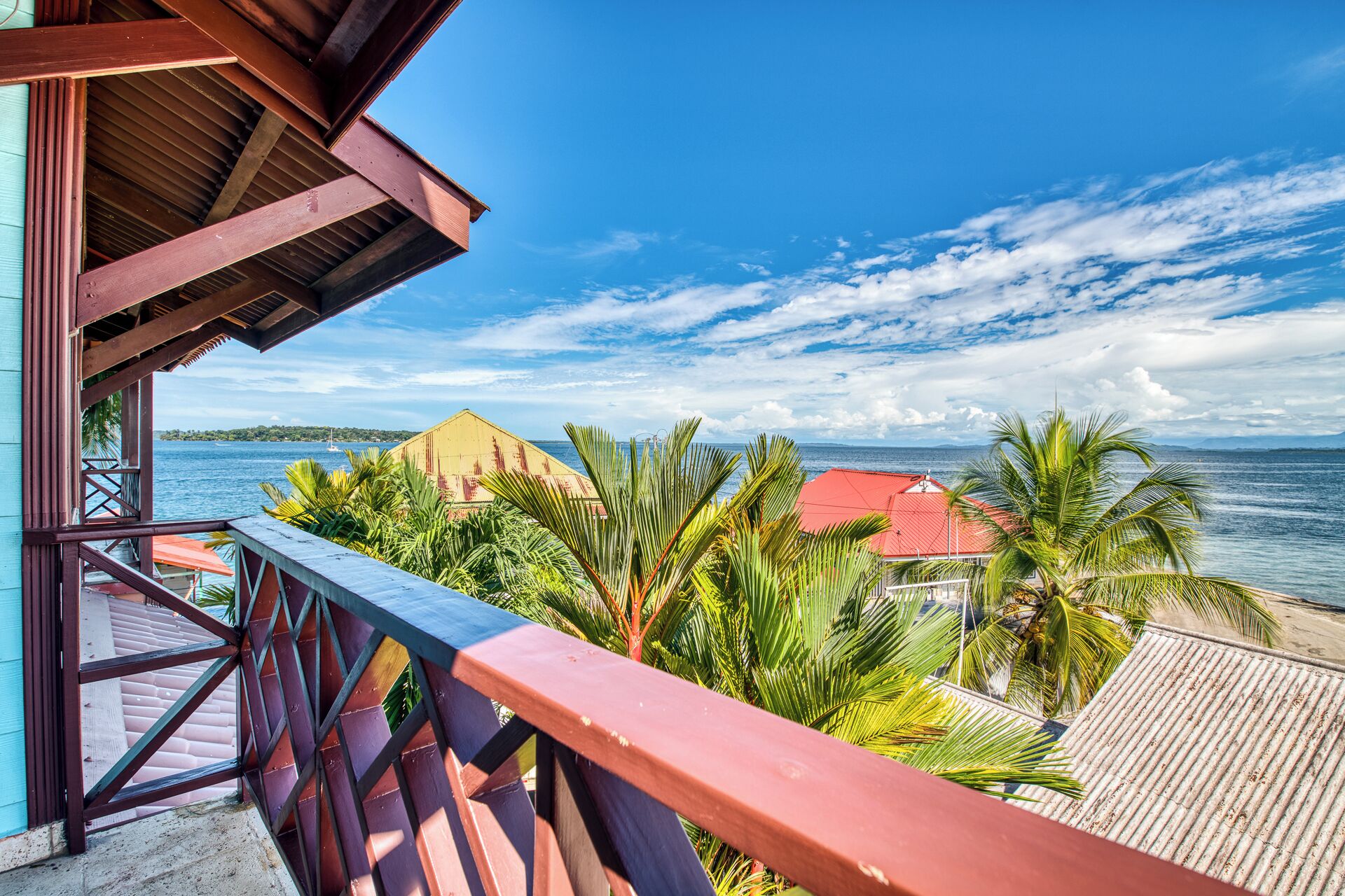 A wooden balcony with a view of the sea and a distant island.