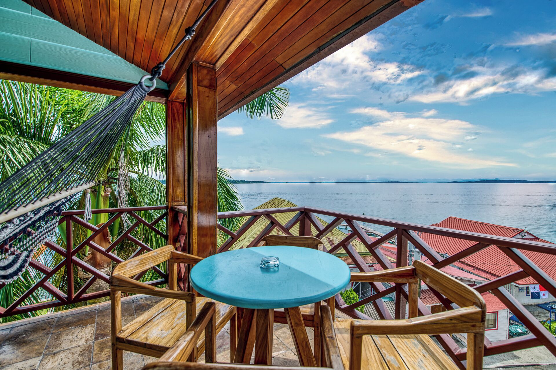 Une terrasse en bois avec une table ronde et des chaises, donnant sur une étendue d’eau sous un ciel dégagé.