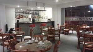 A restaurant with round tables and chairs, a bar area, and a view of the street. - Hotel Libertad (Trujillo)